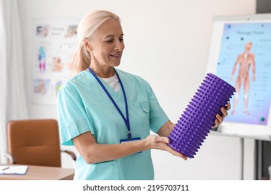 Mature Physiotherapist With Foam Roller In Rehabilitation Center