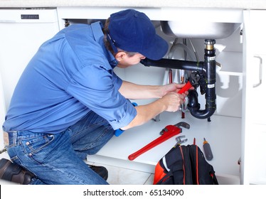 Mature plumber fixing a sink at kitchen
