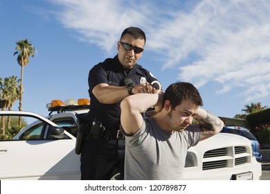 A mature police officer arresting young man