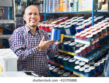 Mature Positive Man Selecting Wall Paint And Emulsion In Household Store