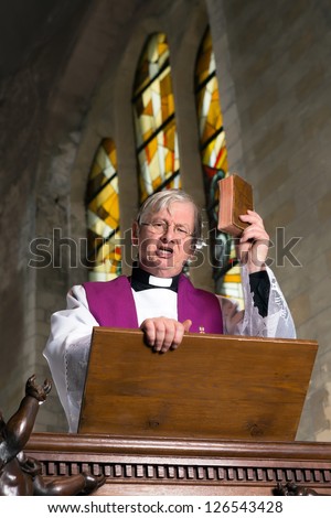 Mature preacher on wooden pulpit during mass