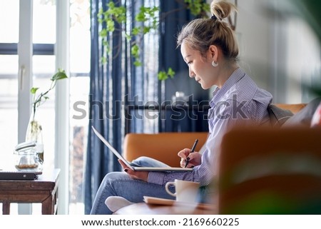 mature professional asian woman working on a paper document from home using laptop computer side view
