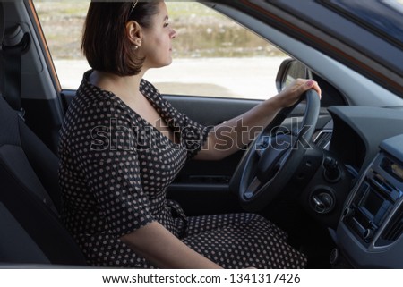 Mature redhead woman sitting behind the wheel of a car with a serious expression on her face