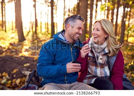 Mature Retired Couple Stop For Rest And Hot Drink On Walk Through Fall Or Winter Countryside