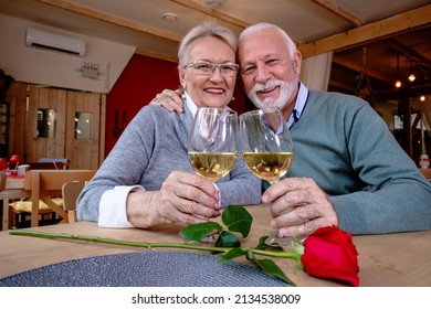 A mature romantic couple of caucasian man and woman sit in a restaurant. Seniors in love, looking at camera, toasting and clinking glasses with wine. - Powered by Shutterstock