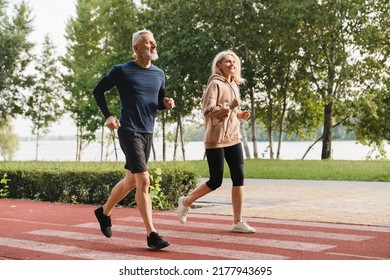 Mature runners couple athletes jogging together in the morning in stadium park. Slimming workout training outdoors. - Powered by Shutterstock