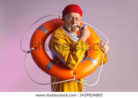 Mature sailor with ring buoy smoking pipe on grey background