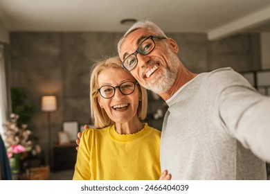 Mature senior caucasian couple husband and wife hold mobile phone and do self portrait hold mobile phone and do self portrait of himself at home - Powered by Shutterstock