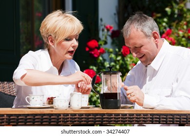 Mature or senior couple having coffee on the porch in front of their home - Powered by Shutterstock