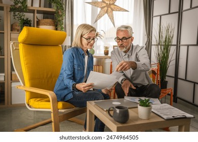 Mature senior couple husband and wife work together form home, man and woman look and talk about documents - Powered by Shutterstock