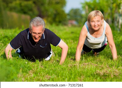 Mature or senior couple in jogging gear doing sport and physical exercise outdoors, pushups