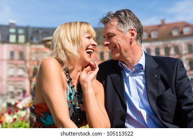 Mature Or Senior Couple Sitting On A Bench During Spring In The City And Enjoy The Sun