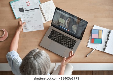 Mature Senior Employer Hr Checking Indian Female Job Applicant Cv Holding Social Distance Remote Online Job Interview By Video Conference Call Virtual Chat Meeting With Recruit On Laptop, Top View.