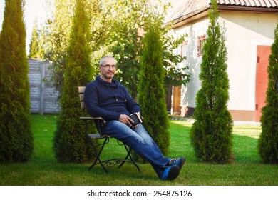 The mature senior man reading novel in country home garden - Powered by Shutterstock