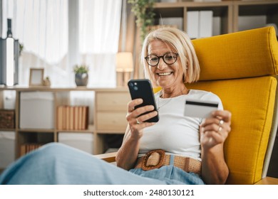 Mature senior woman buy online with credit card and on mobile phone at home - Powered by Shutterstock