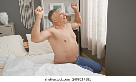 A mature, shirtless man stretching in a modern bedroom, expressing morning freshness and relaxation. - Powered by Shutterstock