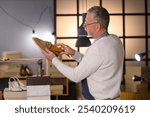 Mature shoemaker putting insole into shoe in workshop