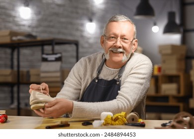 Mature shoemaker repairing shoe at table in workshop - Powered by Shutterstock