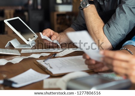 Mature smalll business owners calculating finance bills of their activity. Business people using calculator to work. Closeup hands of man and woman calculating bills and expenses. 