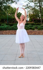 Mature Smiling Woman Dancing Ballet In A Park At Street.