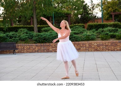 Mature Smiling Woman Dancing Ballet In A Park At Street.