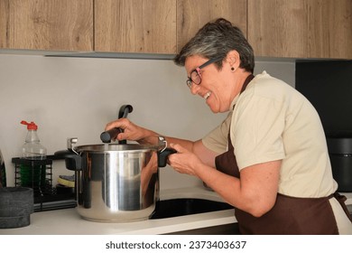 Mature Spanish woman adding water to the stew, cocido madrileño, in a pressure cooker. - Powered by Shutterstock