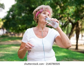 Mature Sportswoman Drinking Water In Park