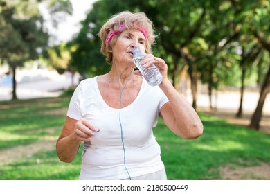 Mature Sportswoman Drinking Water In Park