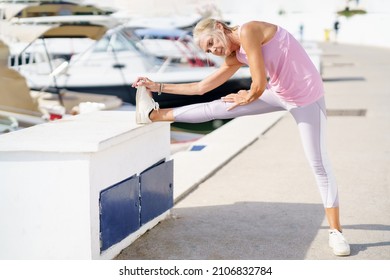 Mature Sportswoman Stretching Her Legs After Exercise.