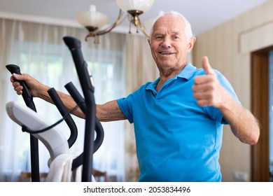 Mature sporty man exercising on an elliptical machine and showing thumb up - Powered by Shutterstock