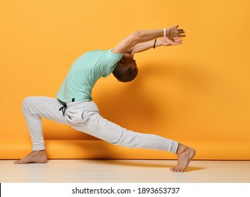 Mature Sporty Man Practicing Yoga Lesson Studio Shot. Handsome Bearded Brutal Male Person Standing In Warrior Doing Stretching Exercise Workout For Back And Shoulders Over Yellow Copy Space