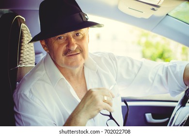 Mature Stylish European Or American Man Wear Black Hat, Glasses And White Shirt Driven Car, Modern And Hipster Style For Older People. Such A Good Mood At Pretty Day