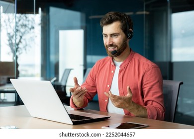 Mature successful businessman with video call headset working inside office, man consulting online clients, talking with colleagues on online remote meeting, sitting at workplace with laptop. - Powered by Shutterstock