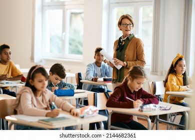 Mature teacher holding a class to group of school kids at primary school. - Shutterstock ID 2144682361