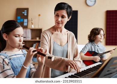 Mature teacher playing musical instruments together with student during musical lesson - Powered by Shutterstock