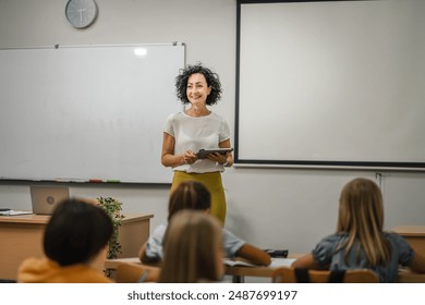 Mature teacher teach a lesson young students and hold tablet in the classroom - Powered by Shutterstock