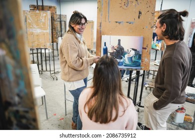 Mature teacher working with art students during painting class at school - Focus on woman face - Powered by Shutterstock