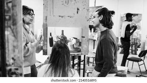 Mature Teacher Working With Art Students During Painting Class At School - Soft Focus On Boy Face - Black And White Editing