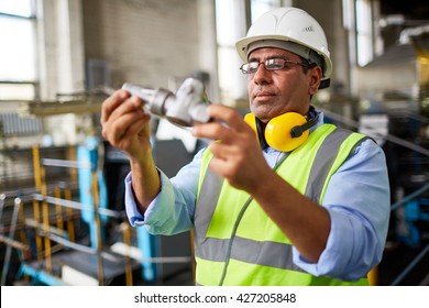 Mature Technician Looking At Detail At Manufacturing