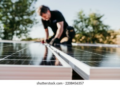 mature Technician man assembling solar panels on house roof for self consumption energy. Renewable energies and green energy concept. focus on foreground - Powered by Shutterstock