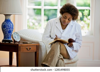Mature Therapist Writing In A Notebook While Alone In Her Office.
