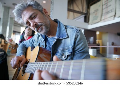 Mature Trendy Guy Playing The Guitar In A Bar