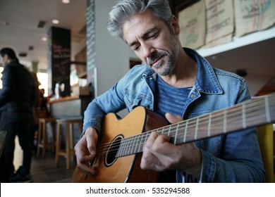 Mature Trendy Guy Playing The Guitar In A Bar