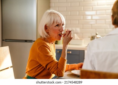 Mature Two Women Eating Cake While Having Lunch Together At Home