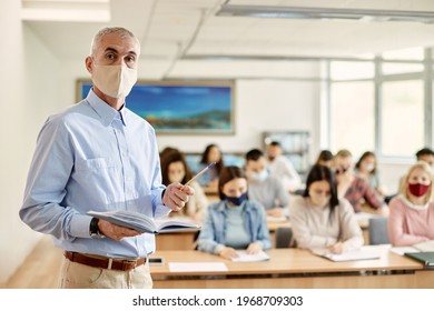 Mature University Professor Wearing Protective Face Mask While Teaching His Students At Lecture Hall.