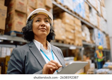 Mature warehouse manager working on digital tablet in storage room. 