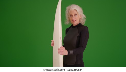 Mature white female surfer posing with surfboard on green screen - Powered by Shutterstock