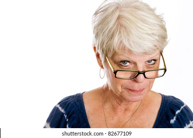 Mature, white haired woman with a skeptical expression on her face while looking over the rim of her glasses.