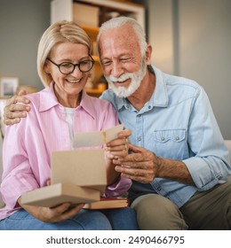 mature wife read greeting card from a gift with her senior husband - Powered by Shutterstock