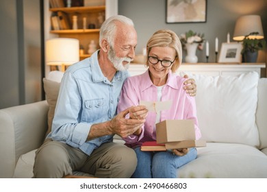 mature wife read greeting card from a gift with her senior husband - Powered by Shutterstock